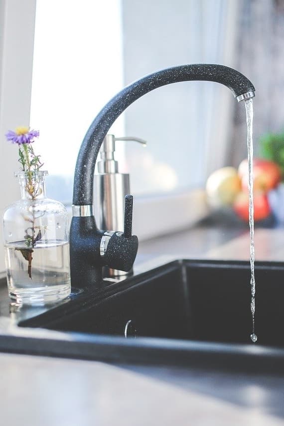 Robinet noir d'évier d'où s'échappe un filet d'eau.