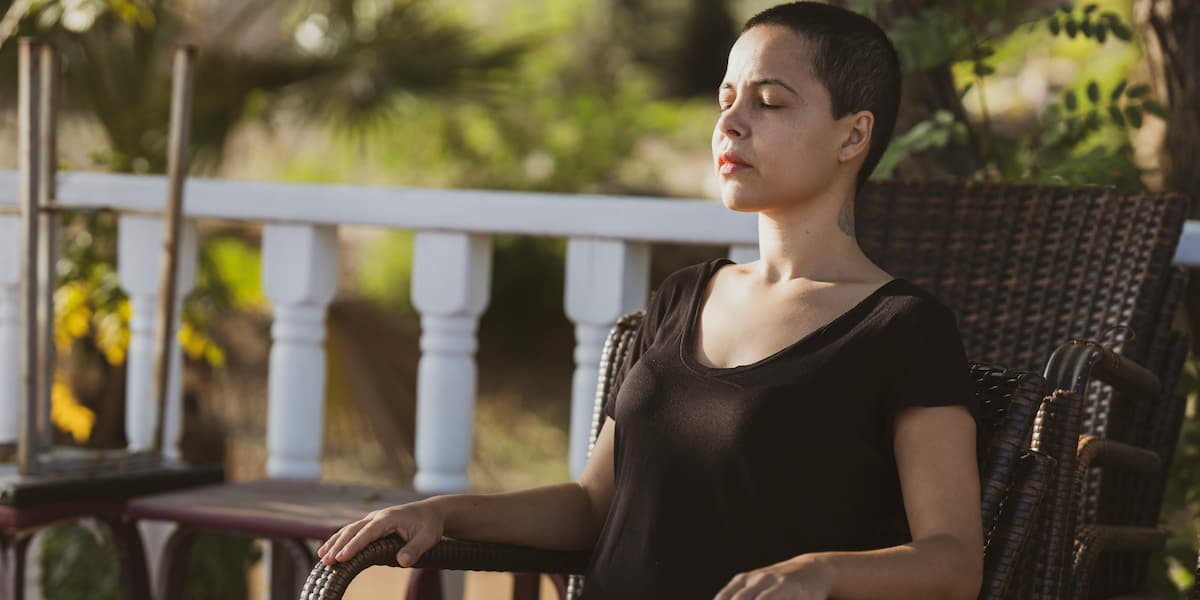 Femme en état d'hypnose, les yeux fermés, assise sur un fauteuil.
